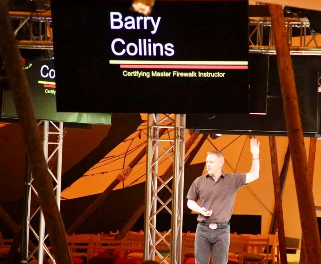Barry Collins of Kick Ash Firewalks Scotland on stage delivering a firewalk to corporate clients